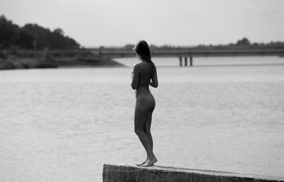 Naked woman walking at beach against sky