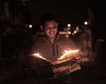 Portrait of young man holding lit candles