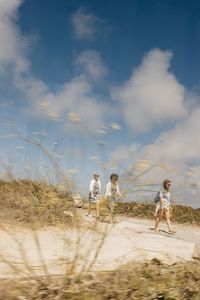 People on sand dune against sky