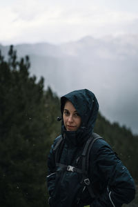 Portrait of a woman standing against forest and sky
