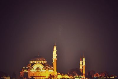 Illuminated mosque against clear sky at night
