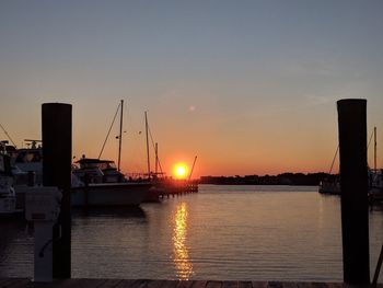 Boats moored at harbor during sunset