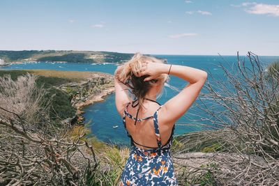 Rear view of woman standing against sea at beach