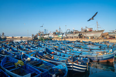 Boats moored at harbor against clear blue sky