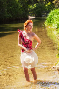 Smiling woman looking away while standing in water