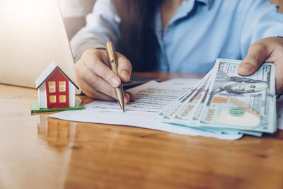 Midsection of woman holding paper while sitting on table