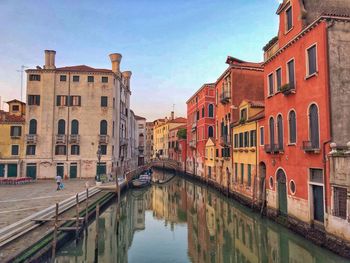 Canal amidst buildings in city against sky