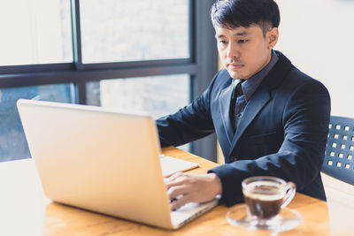 Young man using mobile phone while sitting on table