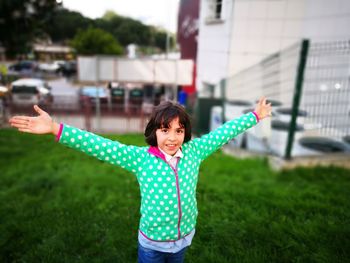 Portrait of girl with arms outstretched standing on field