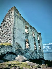 Low angle view of abandoned building against clear blue sky