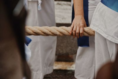 Midsection of people by rope outdoors