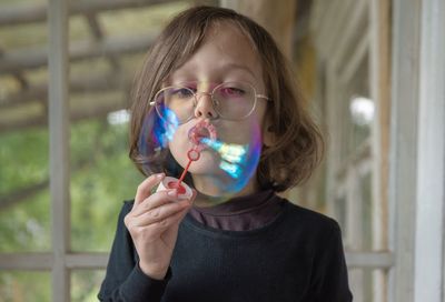 Close-up of boy blowing bubble at home