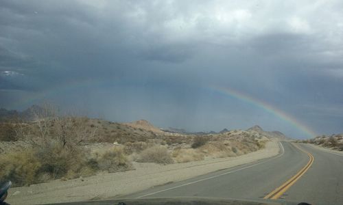 Road by landscape against storm clouds