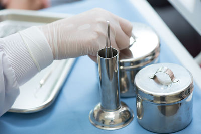 Cropped hand of doctor holding container on table