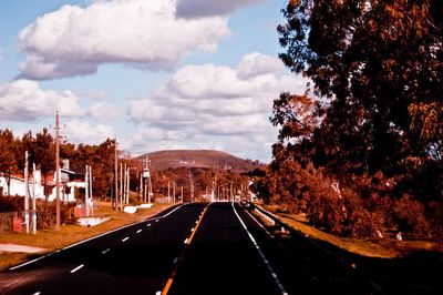 Road by trees against sky