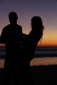 Silhouette of man standing on beach at sunset