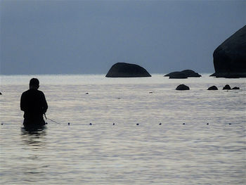 Silhouette man in sea against clear sky