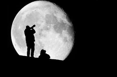 Silhouette people standing against moon at night