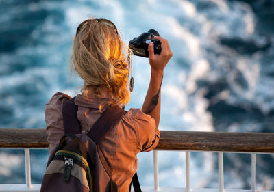 Rear view of woman photographing sea against sky