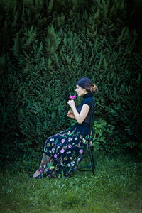 Young pretty woman in black clothes sits on a chair in the garden