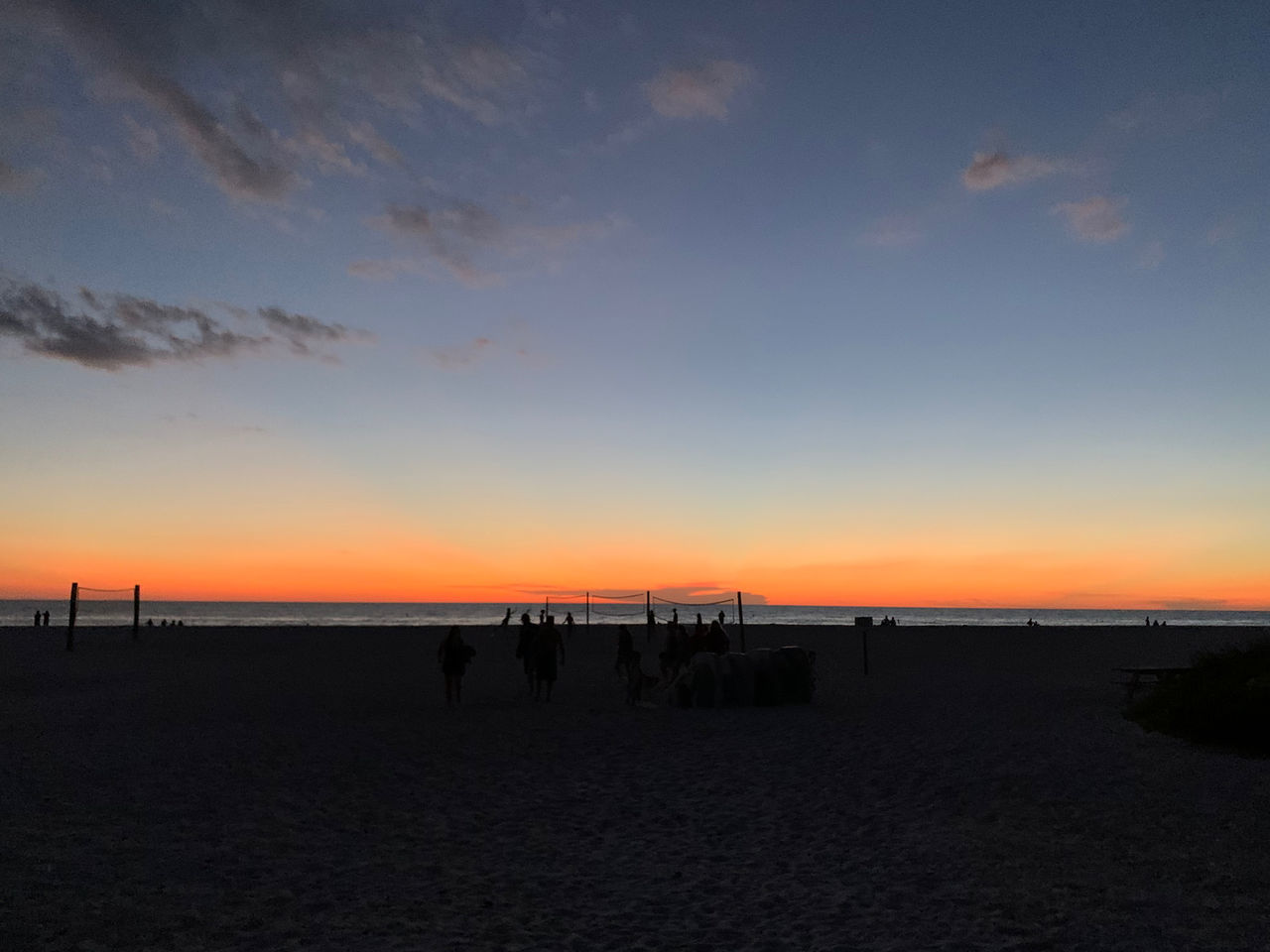 SILHOUETTE PEOPLE ON BEACH AGAINST ORANGE SKY