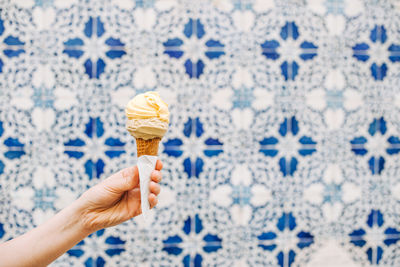 Female hand holding ice cream cone on blurred white blue background