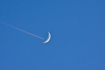 Low angle view of moon against blue sky