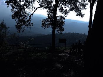 Silhouette trees on landscape against sky at forest