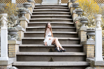 Full length of young woman sitting on staircase