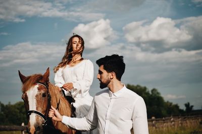 Man with woman riding horse on field