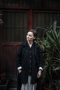 Woman looking up while standing against house 