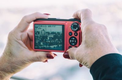 Cropped hand of woman photographing cityscape