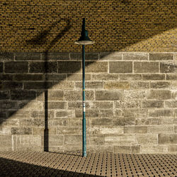 Green street light on sidewalk against brick wall