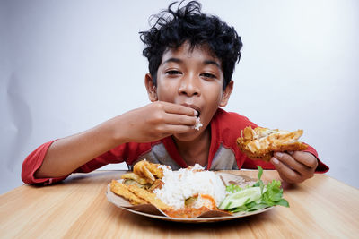 Portrait of young woman eating food at home