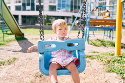 Full length of boy sitting on slide at playground