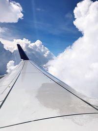 Low angle view of airplane wing over clouds
