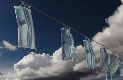 Low angle view shot of masks hanging on clothesline against sky