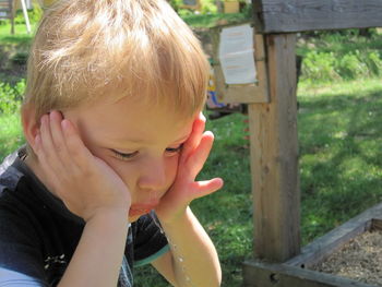 Close-up of boy with hands on chin spitting water at playground