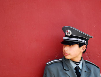 Portrait of man looking away against red wall