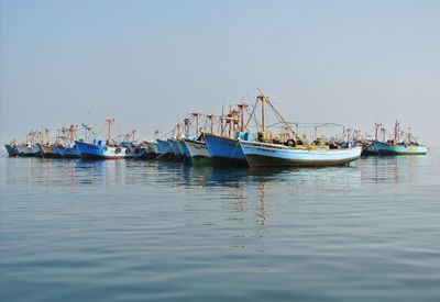 Sailboats moored in sea against clear sky