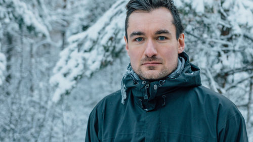 Close-up portrait of mid adult man standing in forest during winter