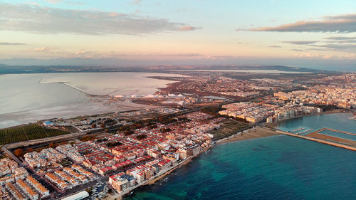 High angle view of buildings by sea against sky during sunset