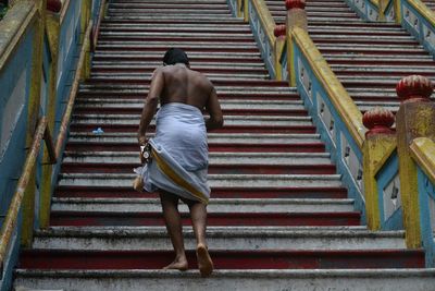 Rear view of man in white lungi climbing steps