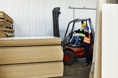 Man talking to worker on forklift in factory