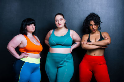 Portrait of smiling women standing against black background