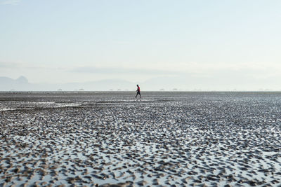 Man standing on pebbles at beach against sky