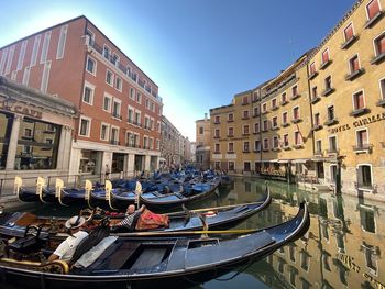 Buildings by canal against sky in city