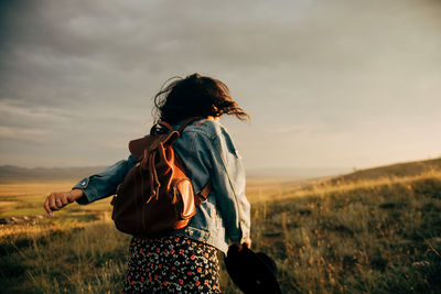 Rear view of woman standing on field against sky