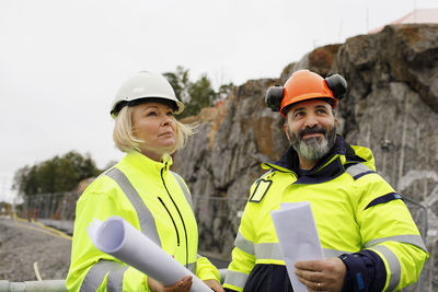 Engineers in reflecting clothing holding blueprints