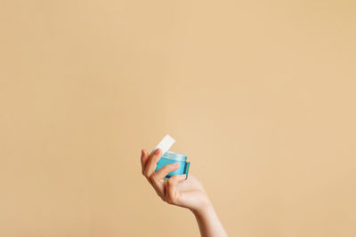 Close-up of hand holding toy against yellow background